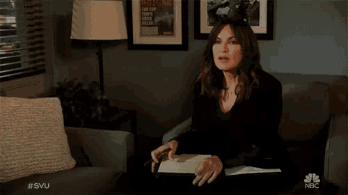 a woman is standing in a room with nbc written on the wall