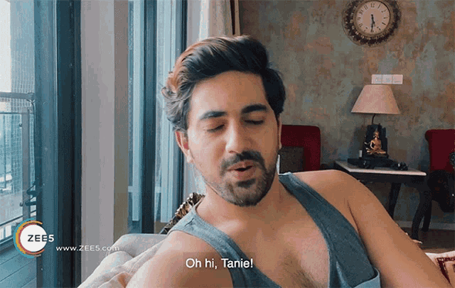 a man sitting on a couch with the words oh hi tanie on the bottom