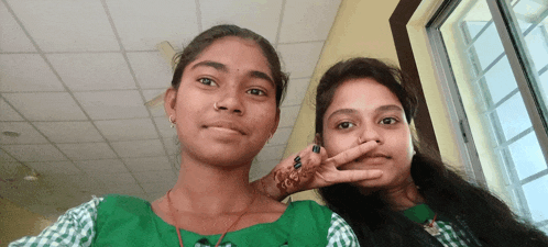 two girls are posing for a picture and one has a peace sign on her finger