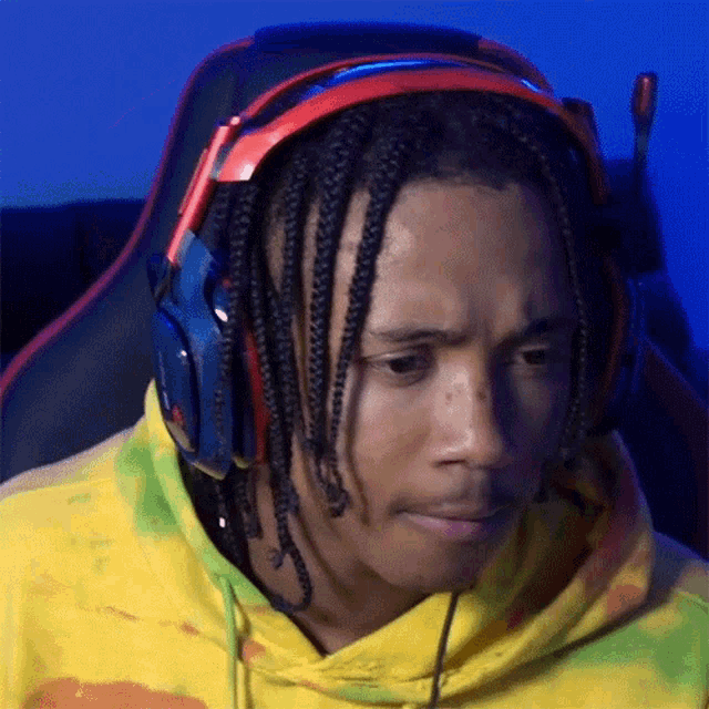 a man with dreadlocks is wearing headphones and a yellow sweatshirt .