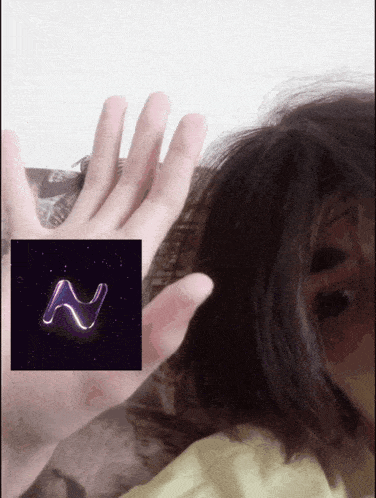a person 's hand is visible in front of a picture of the letter n on a black background
