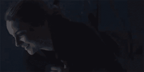 a woman is smiling in a dark room while looking up .