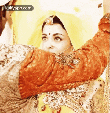 a woman in a yellow and orange dress is being held by a man in a red shirt .