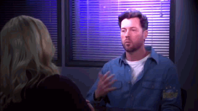 a man in a sheriff 's uniform talks to a woman in front of a window