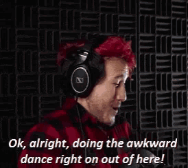 a man with red hair wearing headphones says " ok alright doing the awkward dance right on out of here "