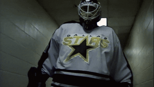 a hockey player wearing a dallas stars jersey and a helmet