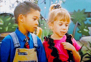 a boy and a girl are standing next to each other and the girl is wearing overalls