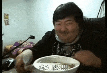 a man is sitting at a table with a bowl of food and a spoon in his hand .