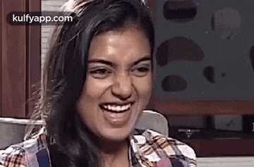 a woman is smiling and making a funny face in a kitchen .