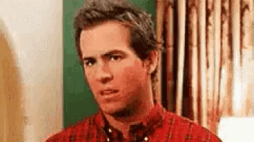 a man in a red shirt is looking at the camera .