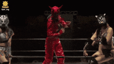 a woman in a red devil costume is dancing in a ring with two other women