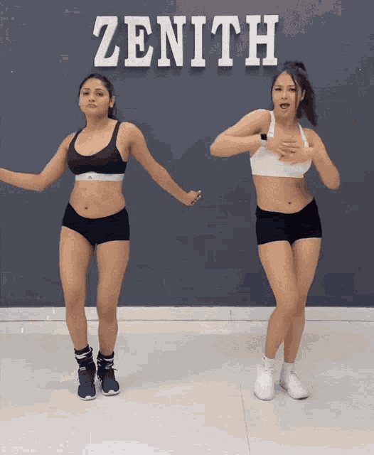 two women dancing in front of a zenith sign