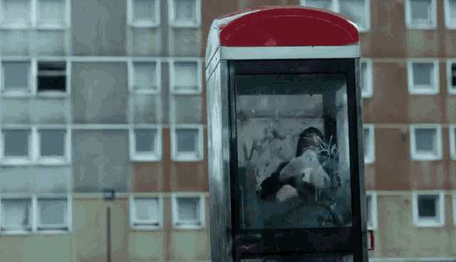 a phone booth with a person inside of it against a building