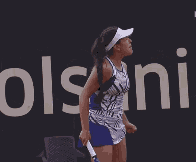 a woman holding a tennis racquet stands in front of a sign that says ccs