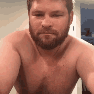 a shirtless man with a beard is standing in front of a door .