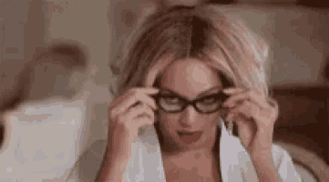 the woman is wearing glasses and a white shirt .