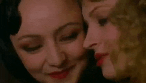 two women are touching each other 's faces in a room .