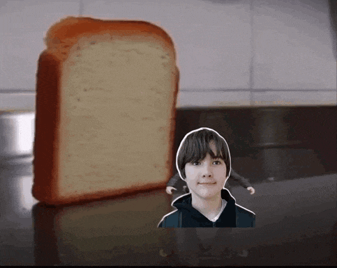 a boy is standing next to a loaf of bread on a counter