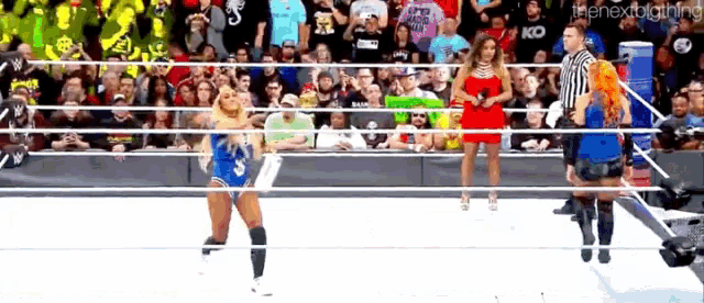 a group of women are standing in a wrestling ring with a referee .