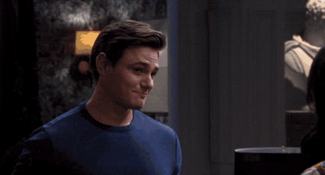 a woman wearing hoop earrings talks to a man in a blue shirt
