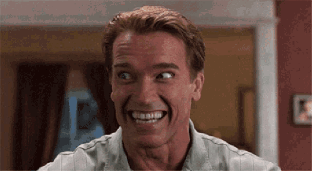 arnold schwarzenegger is smiling and making a funny face in a room .
