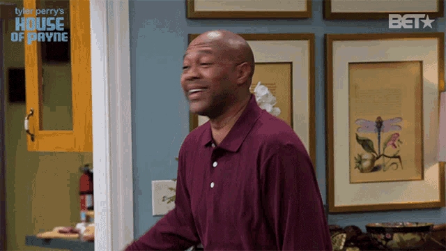 a man in a purple shirt is smiling in front of a sign that says house of payne
