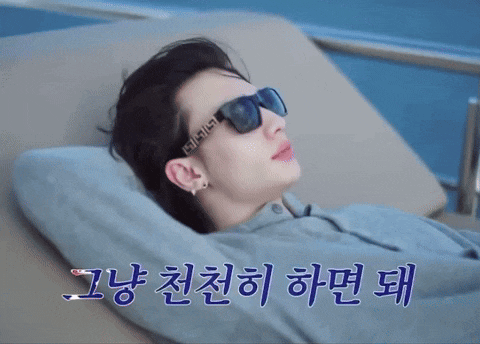 a man wearing sunglasses is laying on a couch with korean writing behind him
