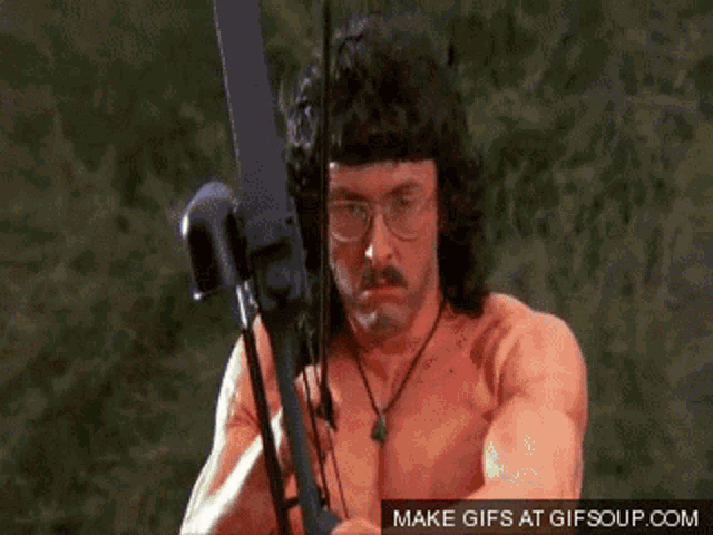 a shirtless man with glasses is holding a bow and arrow with a make gifs at gifsoup.com watermark
