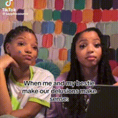 two girls are sitting next to each other in front of a colorful wall . one of the girls is holding a tablet .
