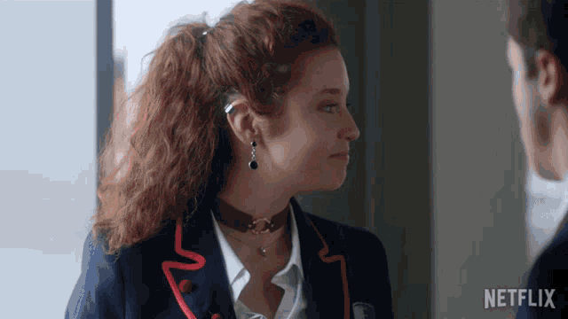 a woman wearing a choker and earrings is standing next to a man with netflix written on the bottom