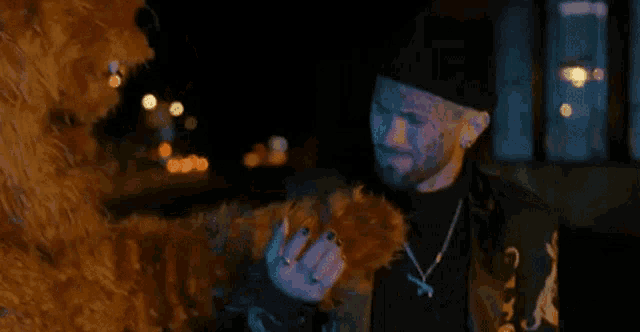a man is holding a stuffed animal in his hand while standing next to a stuffed animal in a dark room .