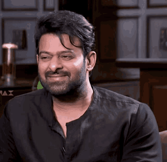 a man with a beard is smiling and wearing a black shirt