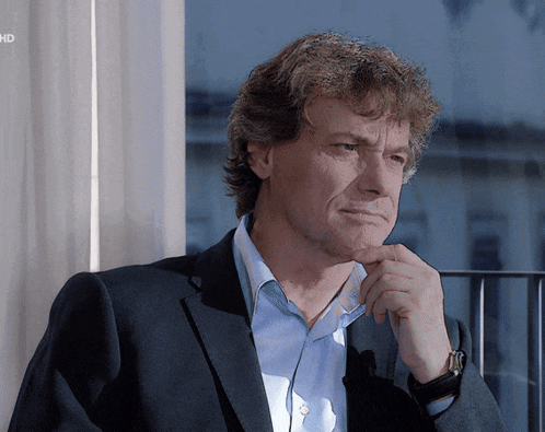 a man in a suit is looking out a window with the word hd visible in the corner