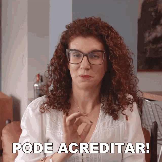 a woman with curly hair and glasses says pode acreditar in a foreign language