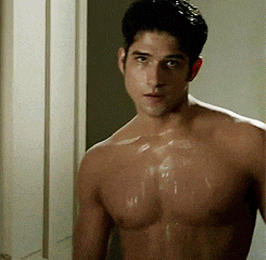a shirtless man is standing in front of a door looking at the camera .