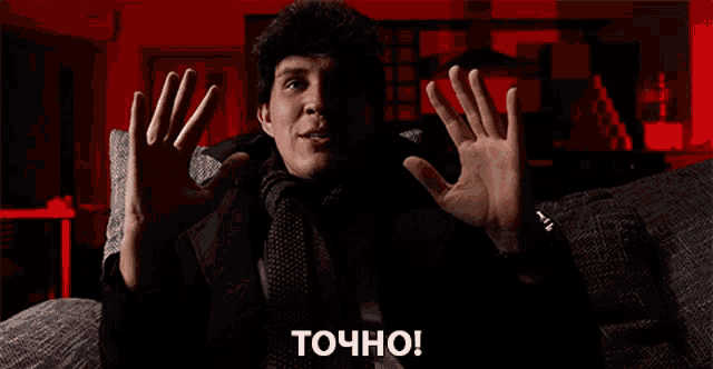 a man is sitting on a couch with his hands in the air and the word точно written on the bottom