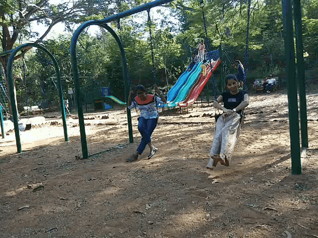 a girl wearing a pink shirt is swinging on a swing