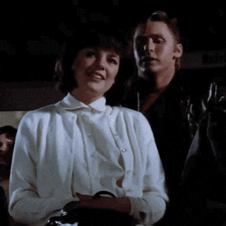 a man and a woman are standing next to each other and the woman is wearing a white cardigan