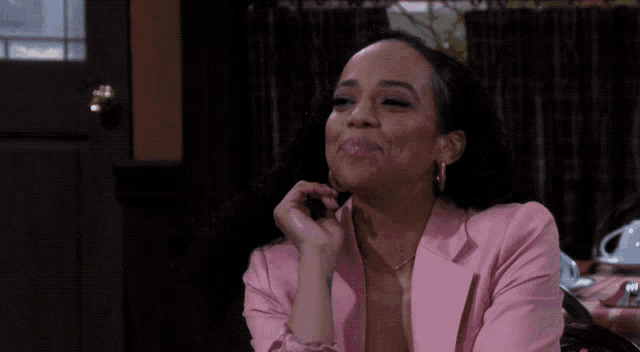 a woman wearing a pink jacket and hoop earrings is smiling