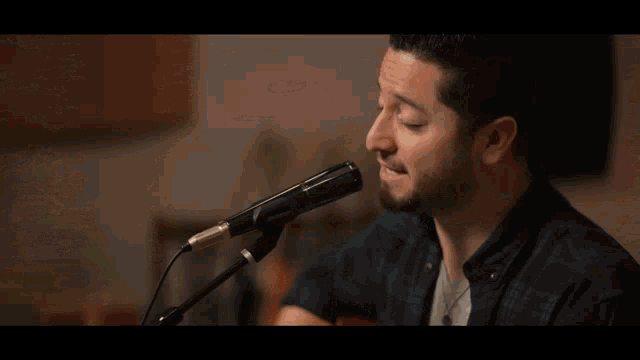a man is singing into a microphone while playing a guitar in front of a mesa amp