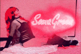 a woman with red hair is laying on the floor with a soma green neon sign behind her