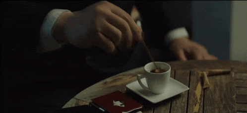 a man in a suit stirs a cup of coffee with a spoon