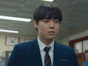 a young man in a suit and tie has a name tag that says ' ae ' on it