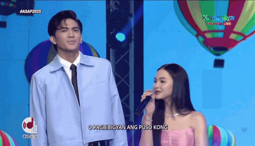 a man stands next to a woman singing into a microphone with the words o pagbibigyan ang puso kong below them