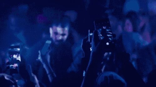 a man is taking a selfie in front of a crowd of people at a party .