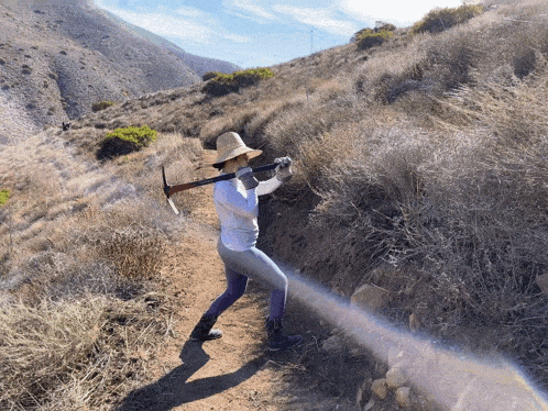 a woman in a straw hat is holding a pickaxe