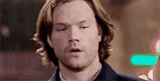 a man with long hair and a beard is making a funny face with his eyes closed and his mouth open .