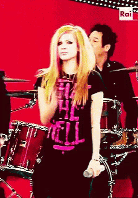 a girl is singing into a microphone while wearing a shirt that says hell on it