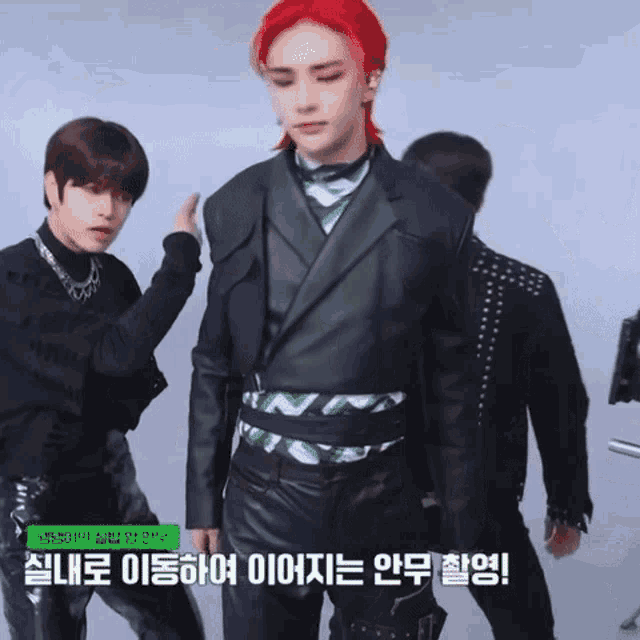 a man with red hair is standing next to another man in a black suit