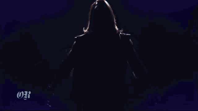 a person with their arms outstretched in a dark room with the letters 031 on the bottom right